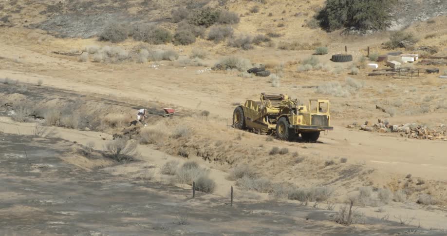 A man is digging up clods of dirt on a property in daylight