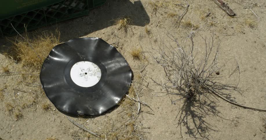 A melted record is sitting in the sand