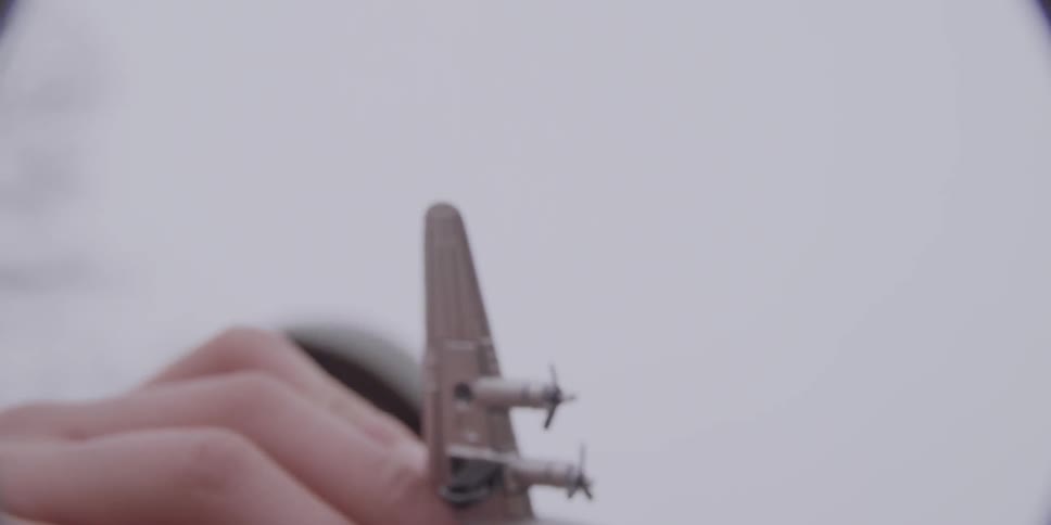 A boy holding a toy airplane and pretending that it is flying