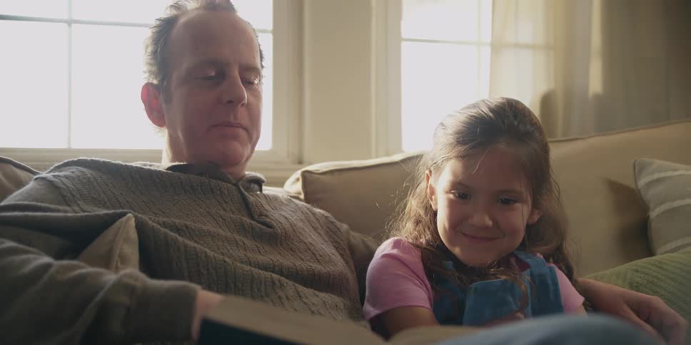 A man reads to a little girl