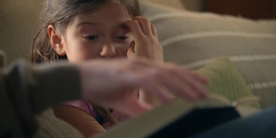 A man reading and chatting with a little girl
