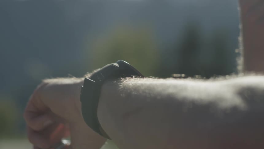 A man is watching his stopwatch outside in daylight