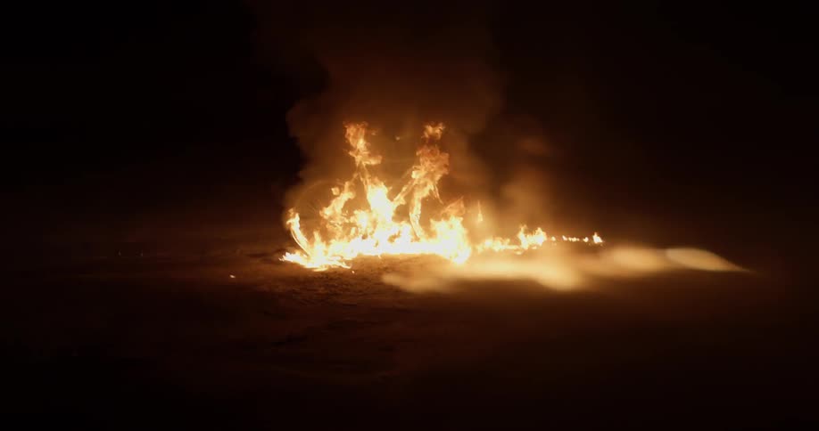 A fire burns on the ground at night