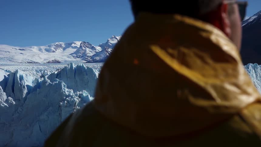 A man is looking at a glacier on a sunny day
