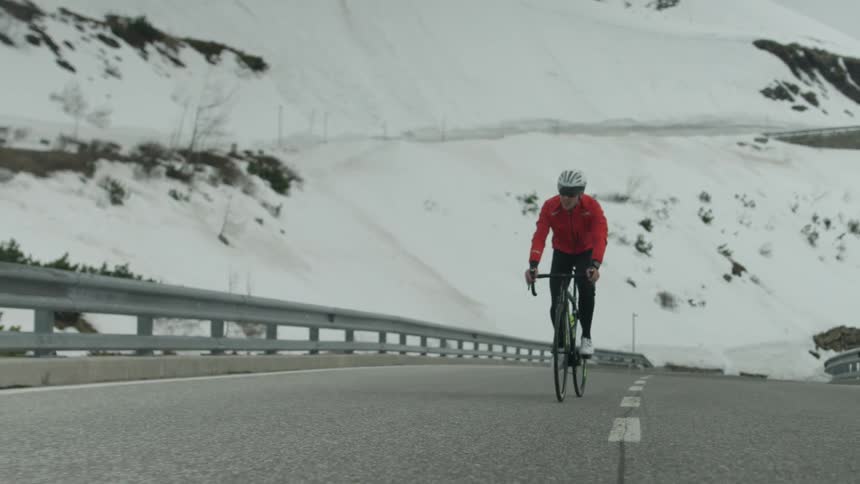 A man is riding his bicycle near the mountain