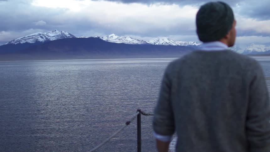 A man walks on a mountain lake dock