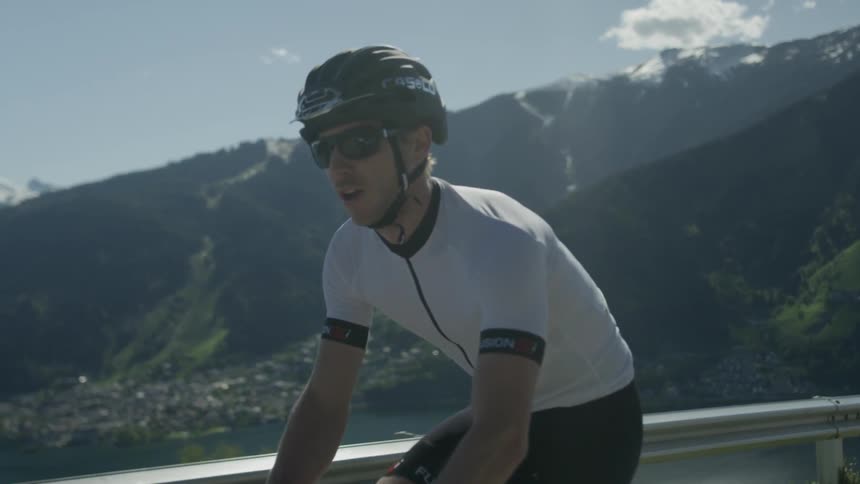 A man is riding a bicycle on a mountain road on a sunny day