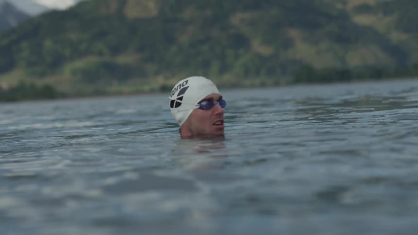 A man swims in a mountain lake
