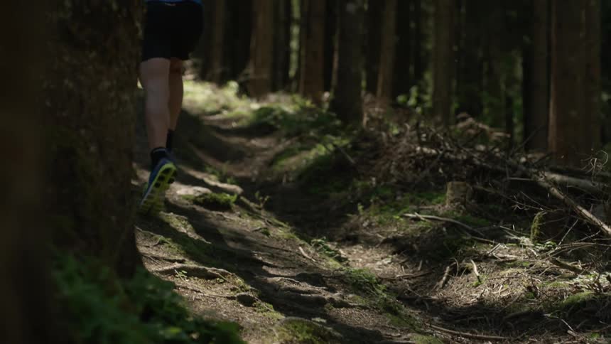 A man runs up a hillside in the woods