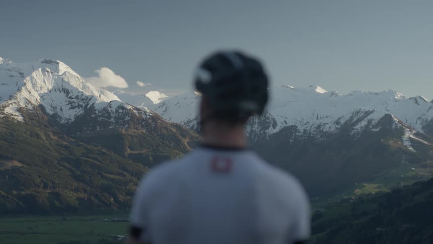 A man looks out onto the snow covered mountains