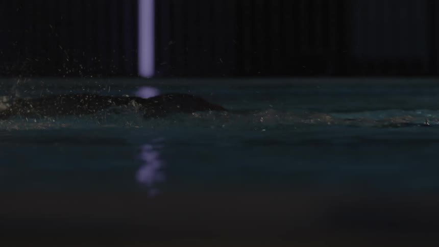 A person is swimming in the dark pool