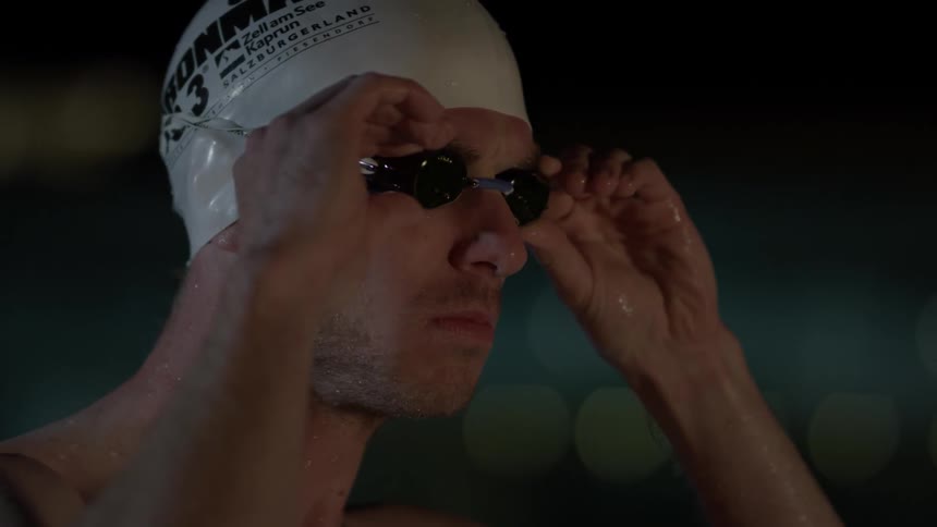 A swimmer puts his goggles on