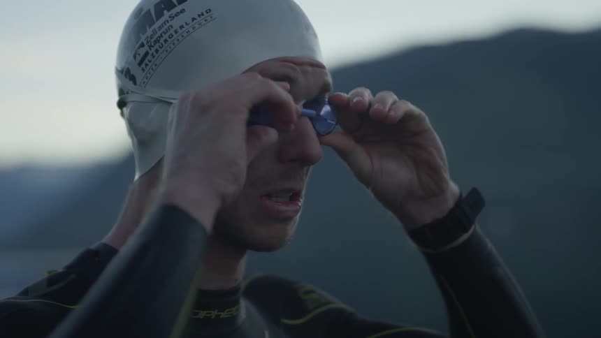 A swimmer puts his goggles on