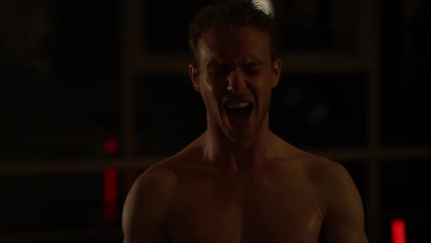 A shirtless man screams while working out