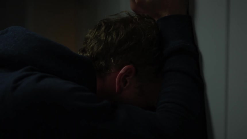 An angry man leans against a wall