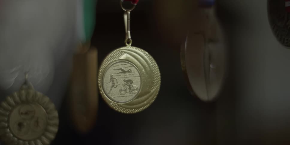 A triathlon medal is hanging in a display case in daylight