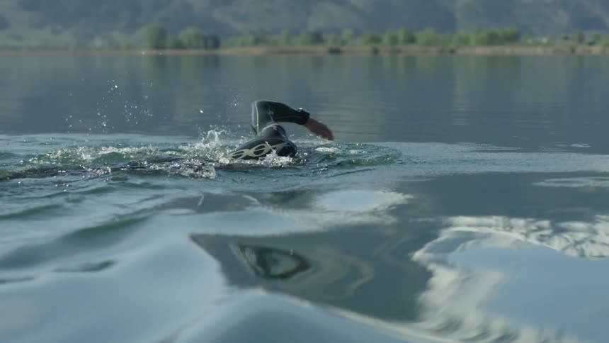 Man swims in a river on a sunny day