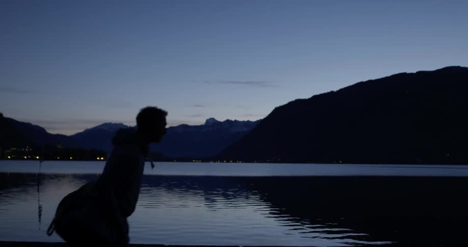 A man carrying a bag walks past the lake at night
