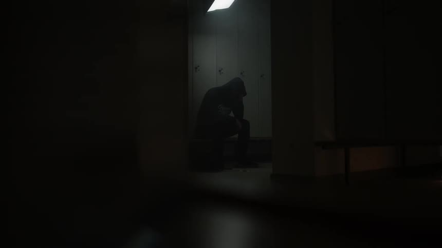 A man sits alone in a locker room