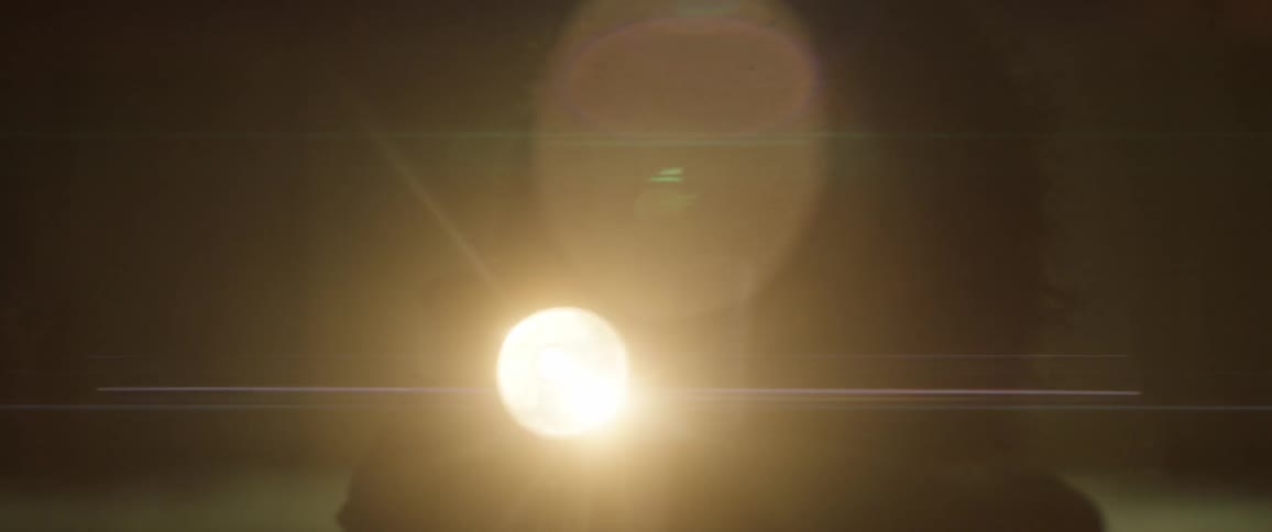 A person holds a flashlight outside at night