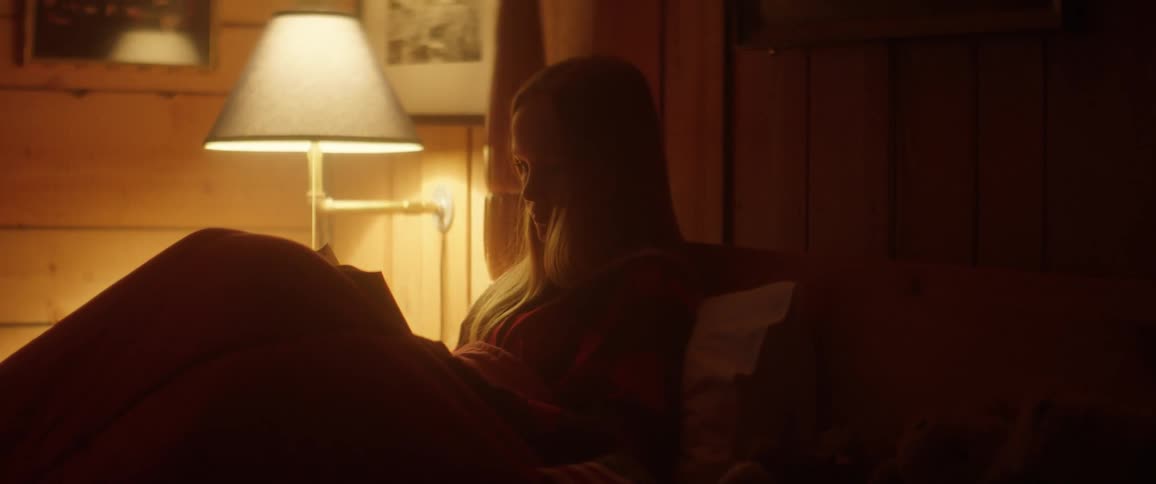 A girl is laying in bed reading at night