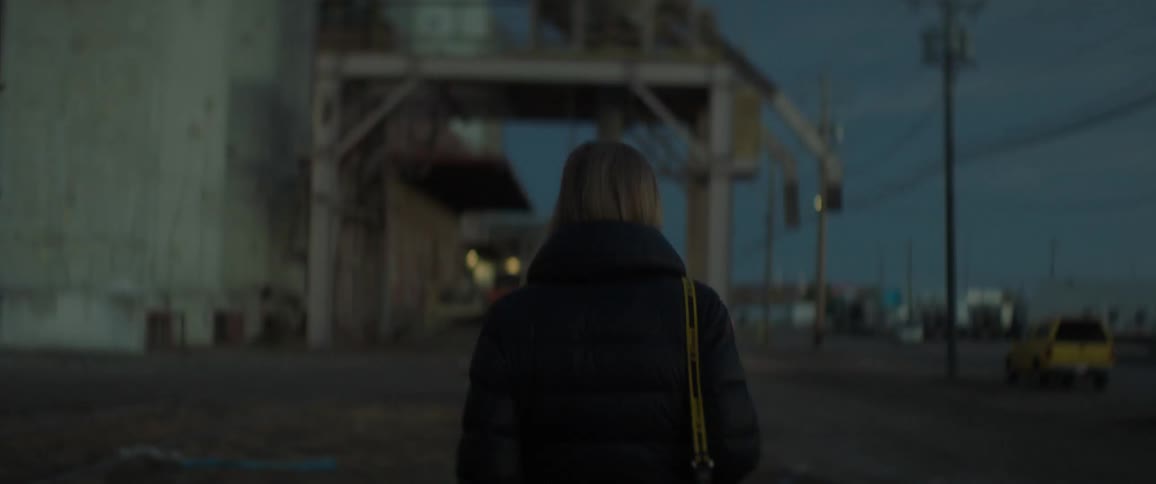 A woman walks next to an industrial building