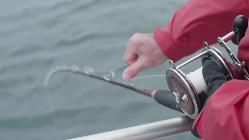 A person is reeling in a fishing pole on a boat