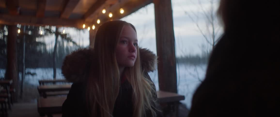 A young woman sits outside at a table