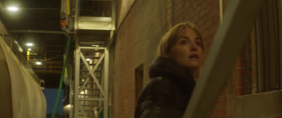 A woman climbs stairs at an industrial building