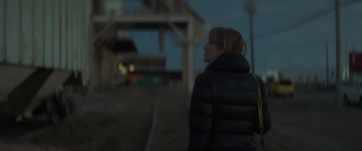 A woman looks back as she walks at sunset