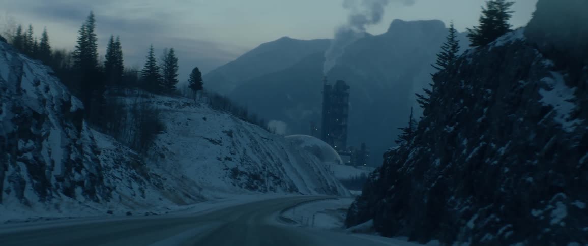 Smoke rises from a tall building in front of a mountain