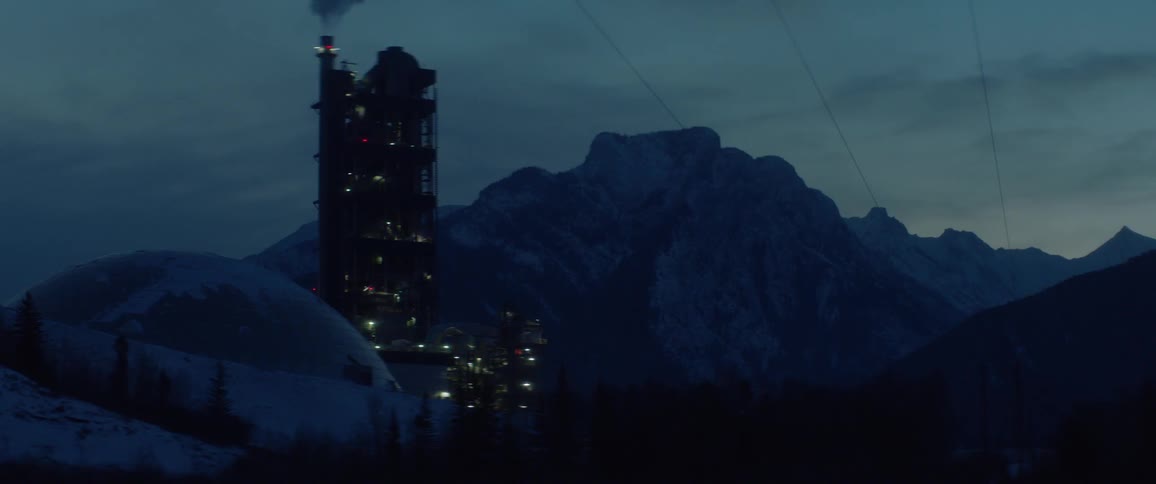 The tall tower sits near the mountain at sunset