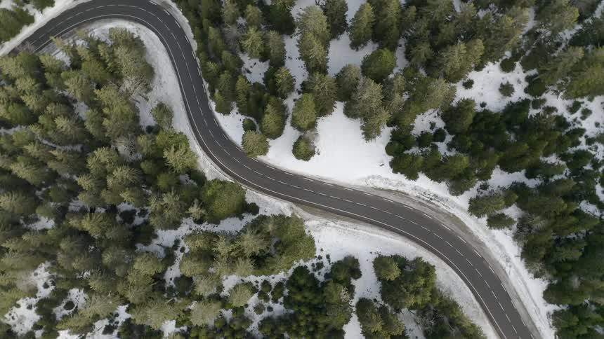 A road is winding through a forest on a winter day