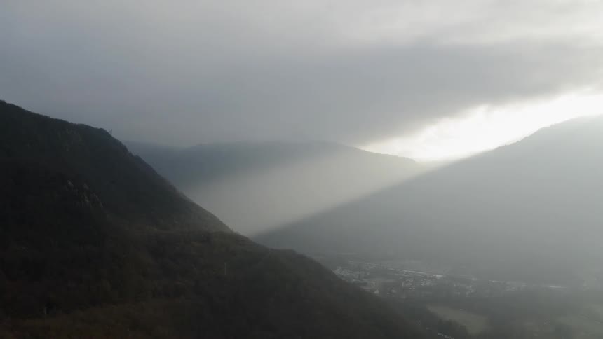 Sunlight shines through the clouds onto a hill
