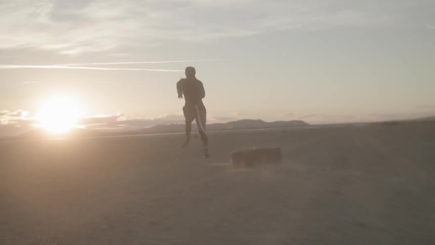 A man runs while pulling a tire in a desert