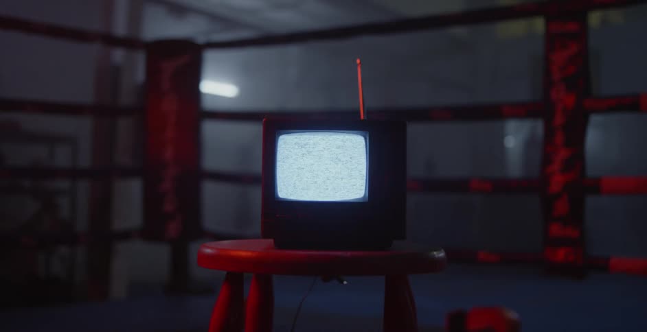 A small television displays static in a boxing ring