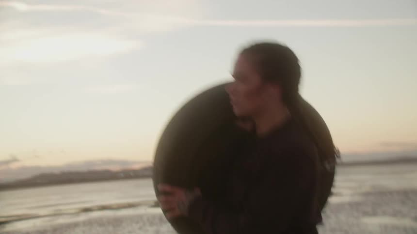 A woman carries a tire on the beach