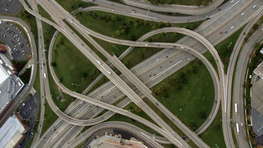 Vehicles are driving on a complex freeway interchange in daylight