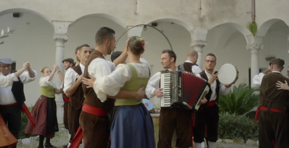 Couples dance around musicians in a courtyard