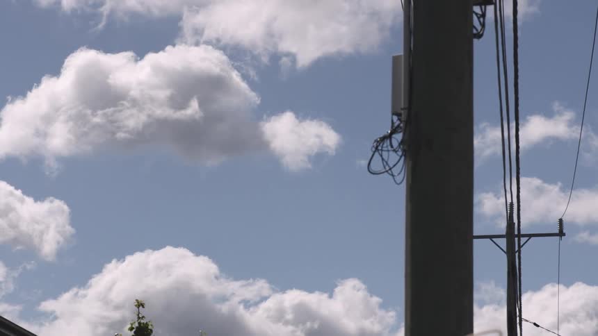 A electric pole as clouds pass behind it