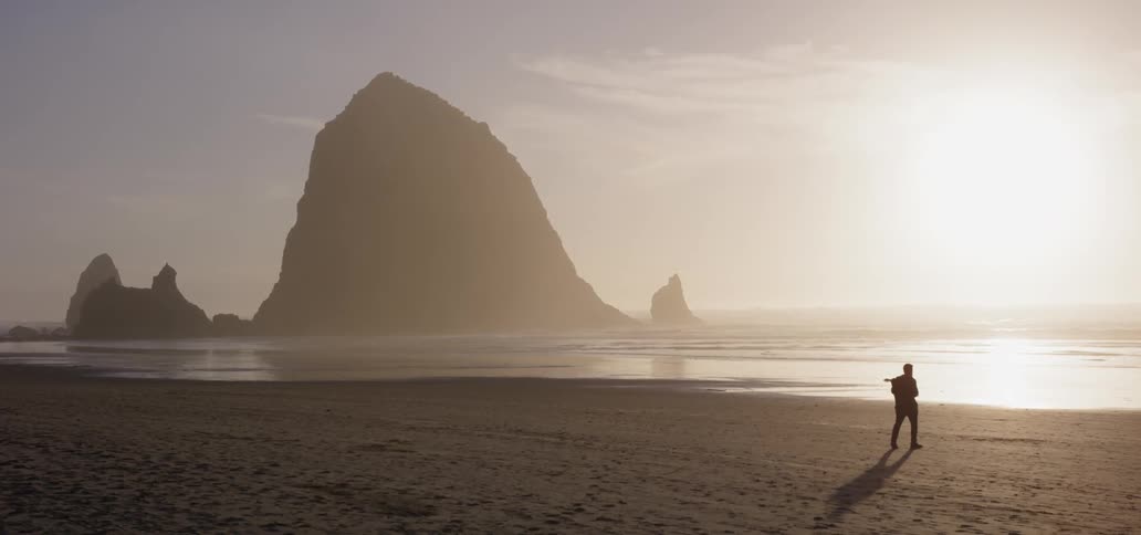A man walks on the beach at sunset