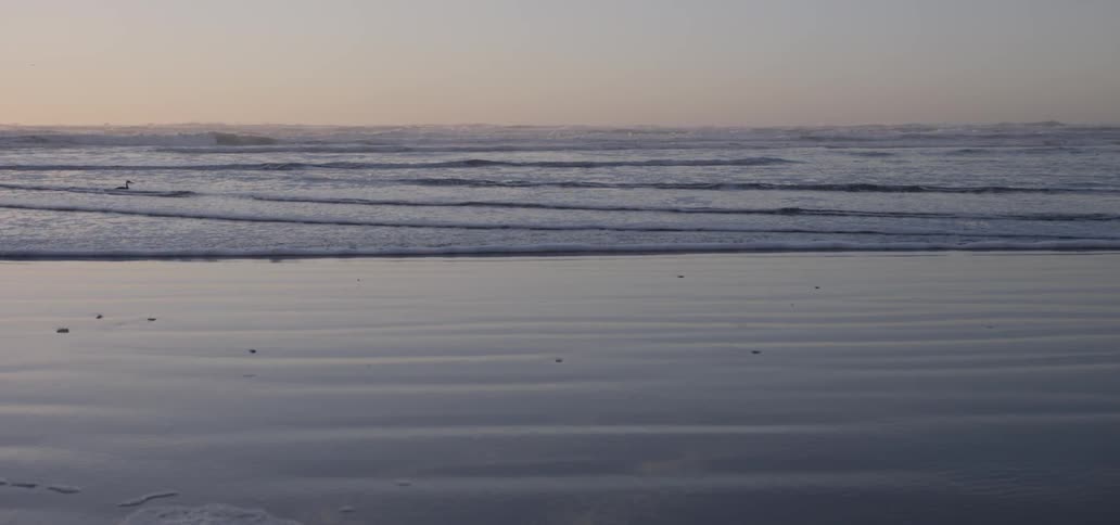 Ocean waves wash ashore at sunset