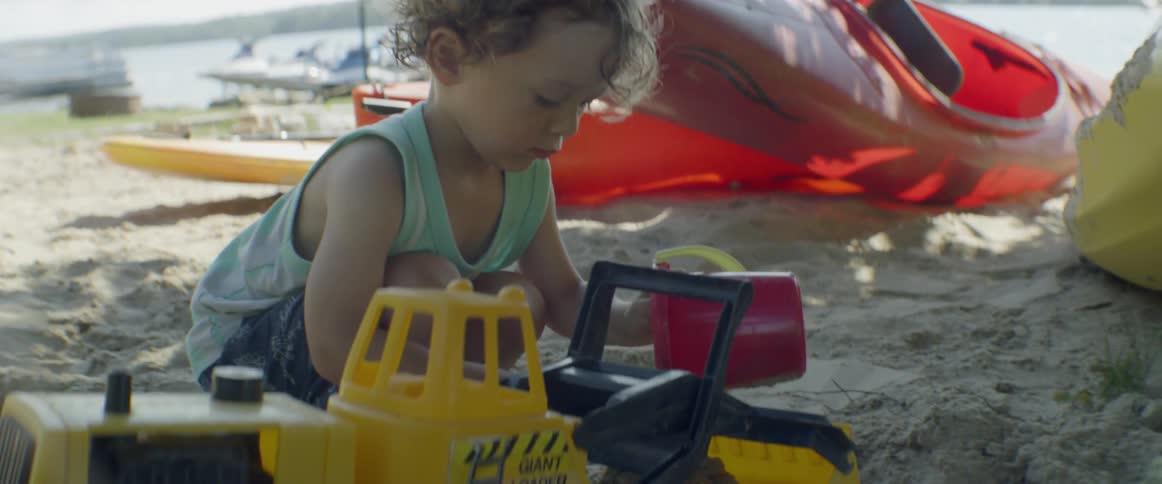 Child on the beach plays with sand toys on a cloudy day