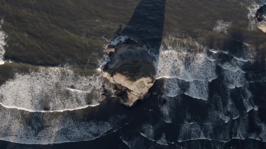 Ocean waves flow around a rock formation