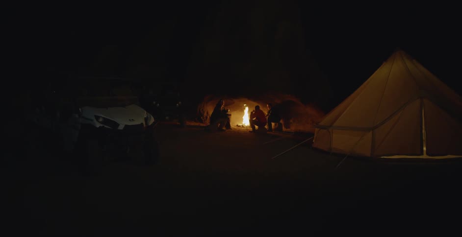 Campers gather around a fire at a campsite
