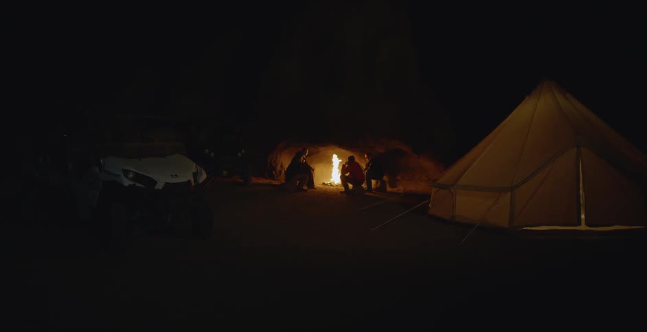 People gather around a fire at a campsite