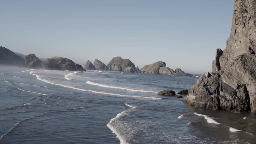 Ocean waves flow around rock formations on a beach