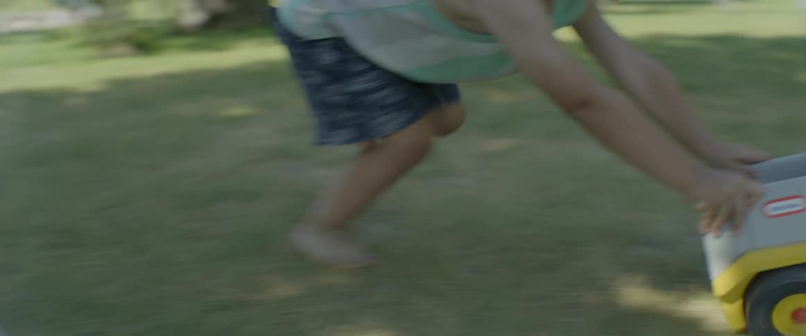 Boy in yard plays with toy truck