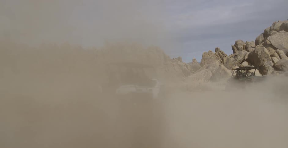 Dune buggies kick up a clouds of sand and dirt as they make a u turn