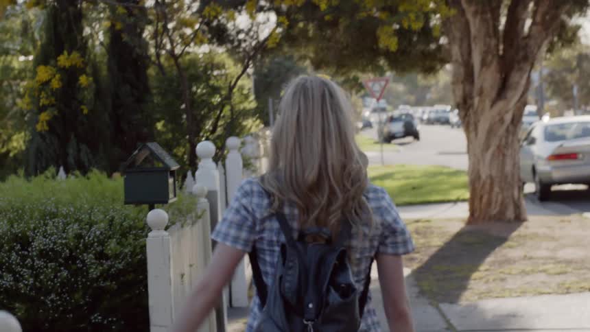 Woman traces her hand across fences as she walks